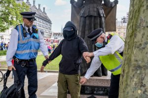 An Extinction Rebellion protestor is searched by two Metropolitan Police Officers during a protest in 2020. 