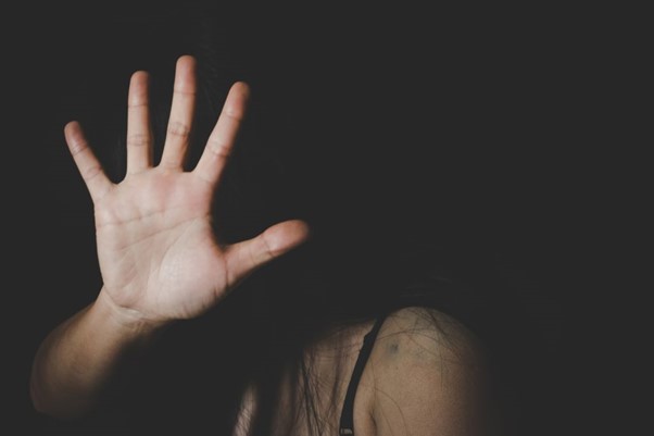 Image of a woman holding her hand over her face to stop someone