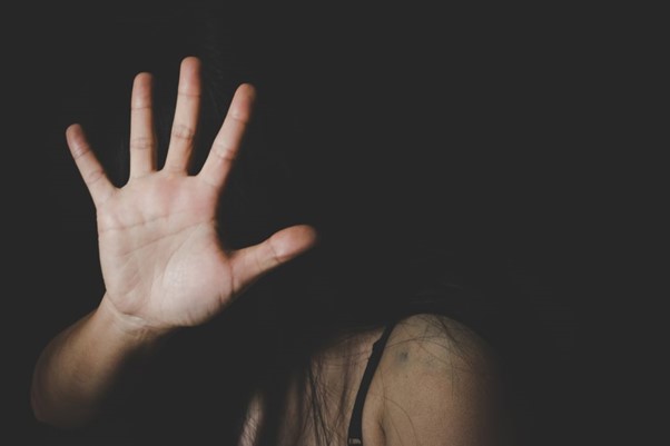 Image of a woman holding her hand over her face to stop someone 