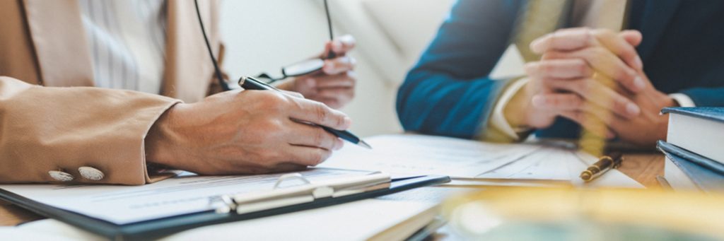 Image of a solicitor sat at a desk with a client, with papers in front of them