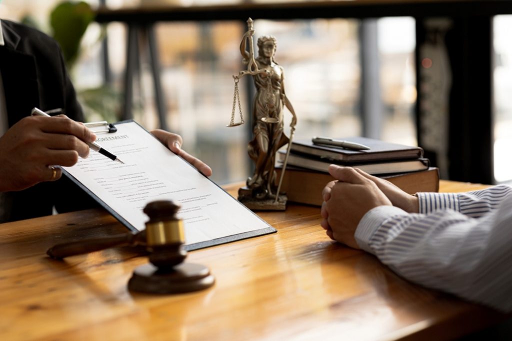 Image of a solicitor handing a client a clipboard with a form to sign on 