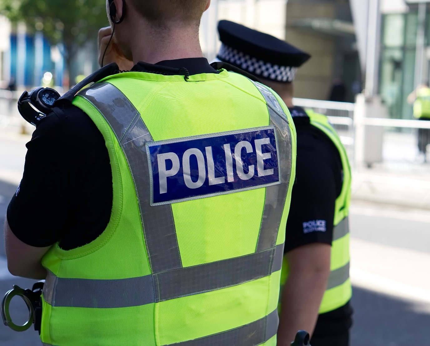 Image of the back of a police officer wearing a high-vis vest which says 'Police' on the back