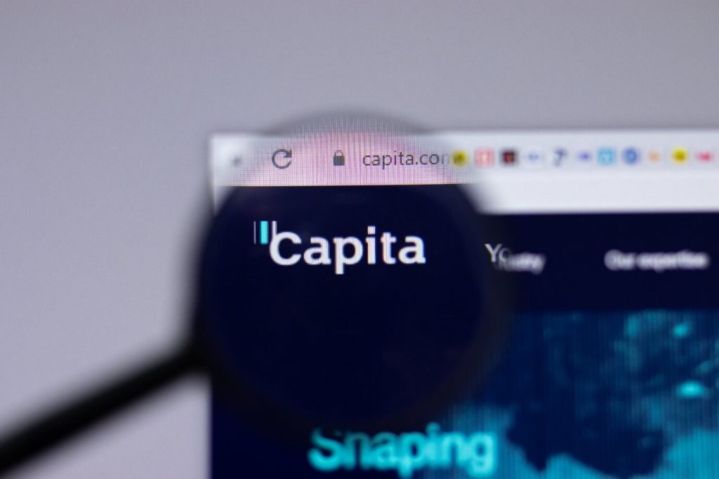 Image of the Capita website with a magnifying glass in front of it magnifying the Capita symbol.