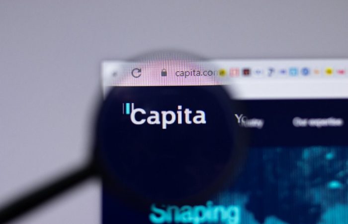 Capita data breach concept image. Image of the Capita website with a magnifying glass in front of it magnifying the Capita symbol.