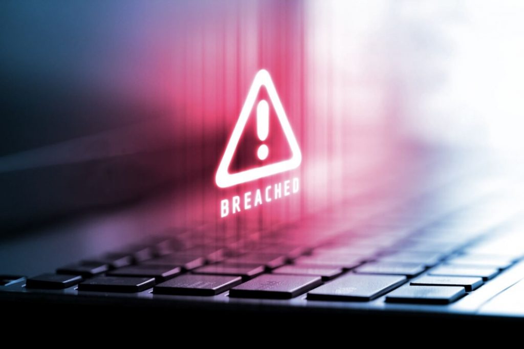 Image of a keyboard up close with a red neon warning symbol above the word 'BREACHED' hovering over the keyboard