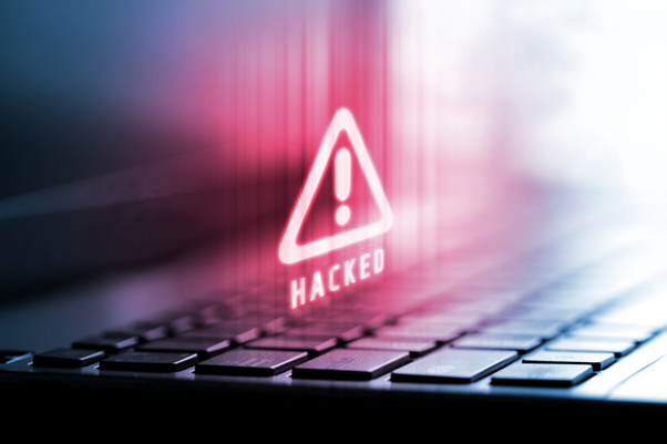 Image of a red warning symbol and the words 'hacked' over a laptop keyboard. Cybersecurity image concept.