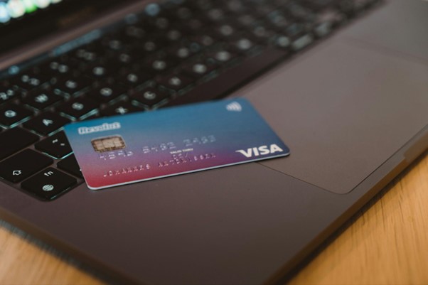 A picture of a revolut debit card lying on top of an open dark grey laptop 