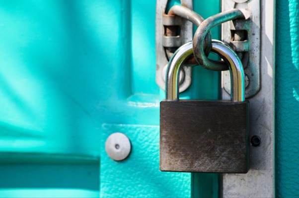 A picture of a metal padlock locking a bright turquoise door.