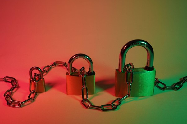 Security concept image, three padlocks lined up next to each other from small to large with a metal chain running through them.