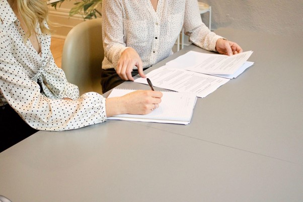 A picture of two women sat behind a desk reviewing paperwork