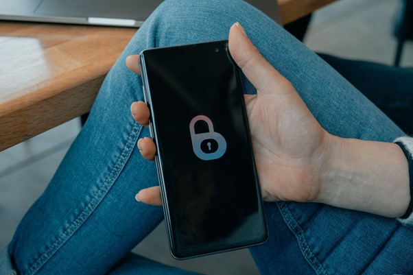 A photograph of a person holding a phone with a padlock symbol on the screen. 