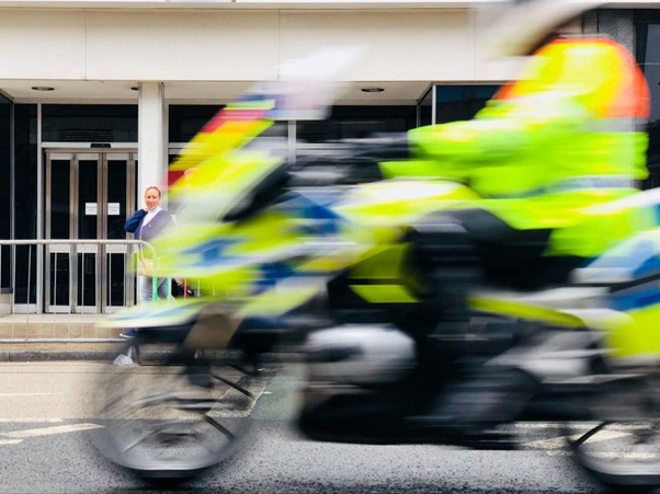 A picture of a police officer riding a police motorbike speeding down a street.