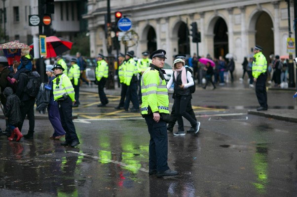 Photograph of several police officers stood on a busy street in the rain