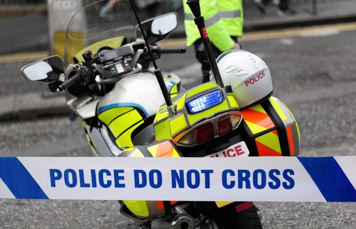 Policeman and police motorcycle behind cordon tape at an accident or crime scene