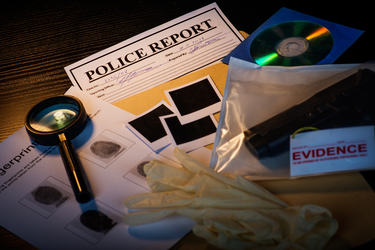 Fictious police desk with crime case records containing gun, blank photos, crime scene information sheet, cd rom, magnifying glass, gloves and police reports