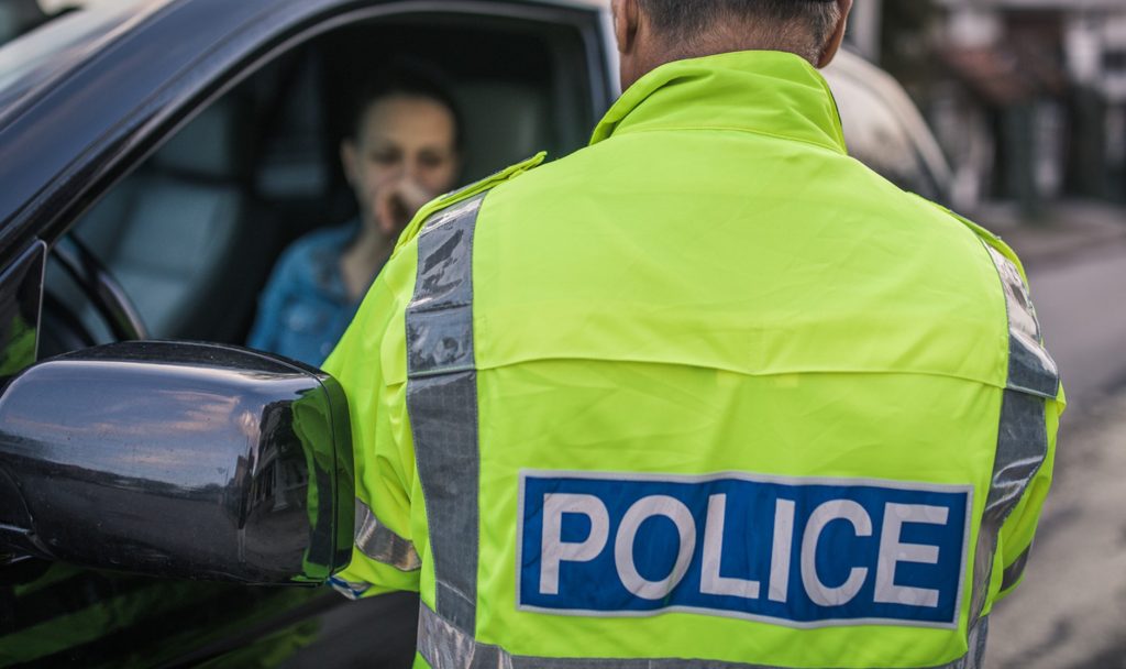 A police officer talking to a woman through her car window after pulling her over