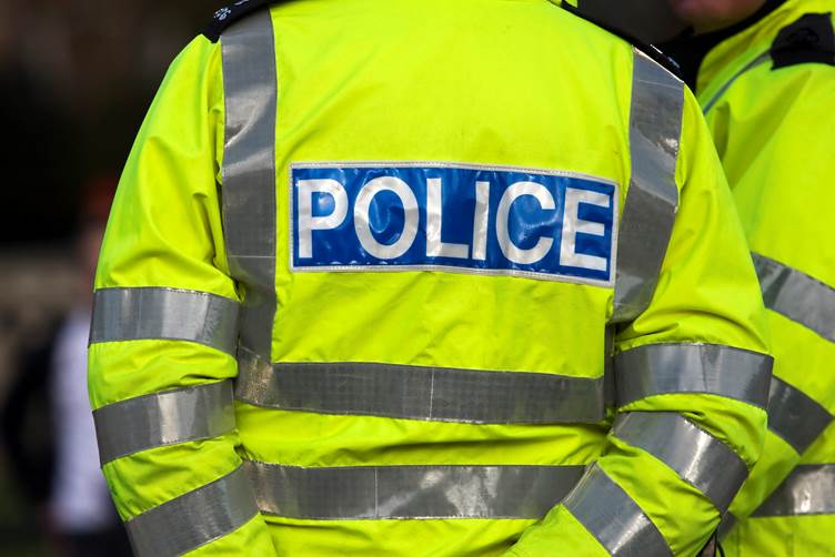 Close up image of the back of a police officer's high visibility jacket which says 'POLICE' on the back