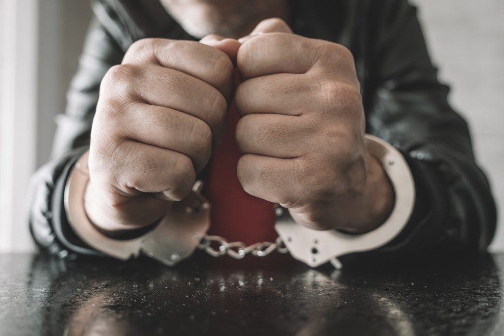 a person handcuffed is sat inside police interview room.