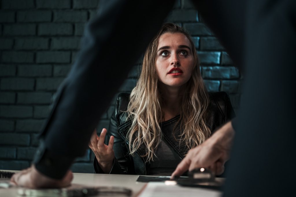 Arrested woman being interviewed by a police detective in a police interview room