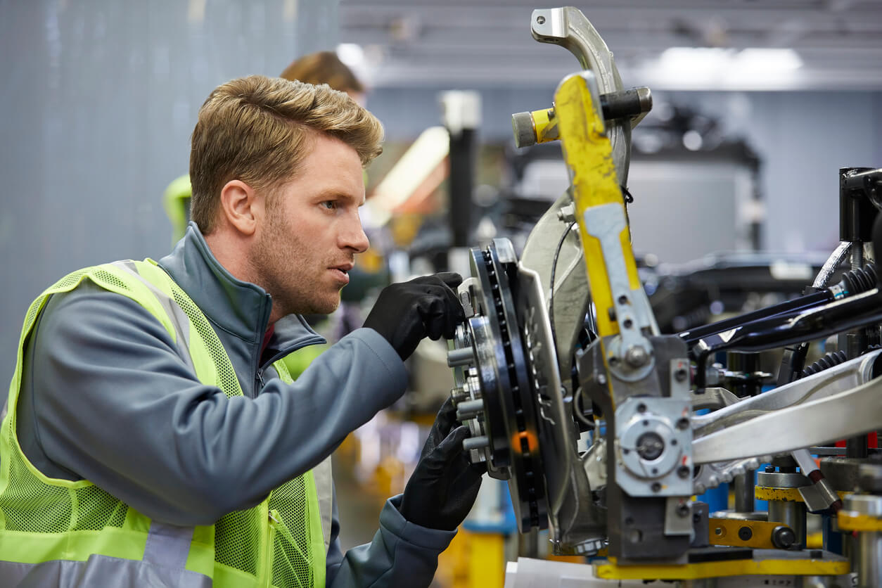 Picture of a worker in a high vis working on manufacturing car parts