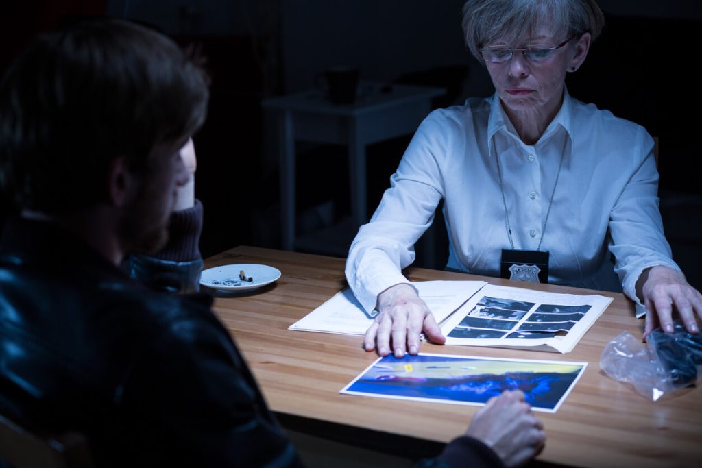 Police woman showing pictures and evidence of crime to suspect