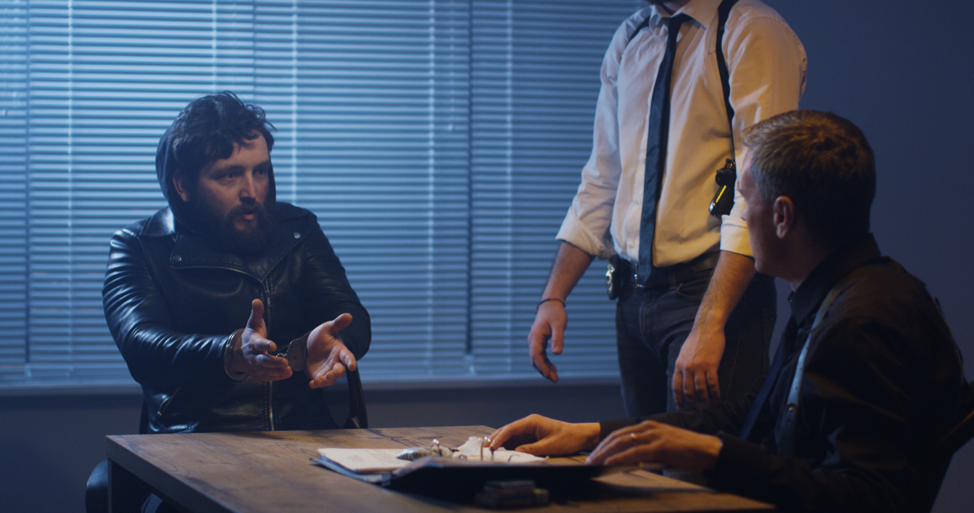 Picture of two police detectives interviewing someone in an interrogation room