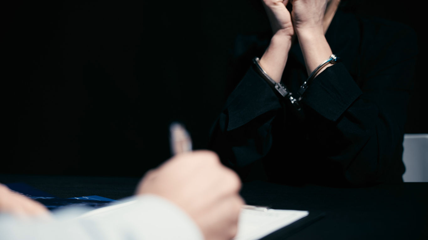 A person in handcuffs being interrogated 
