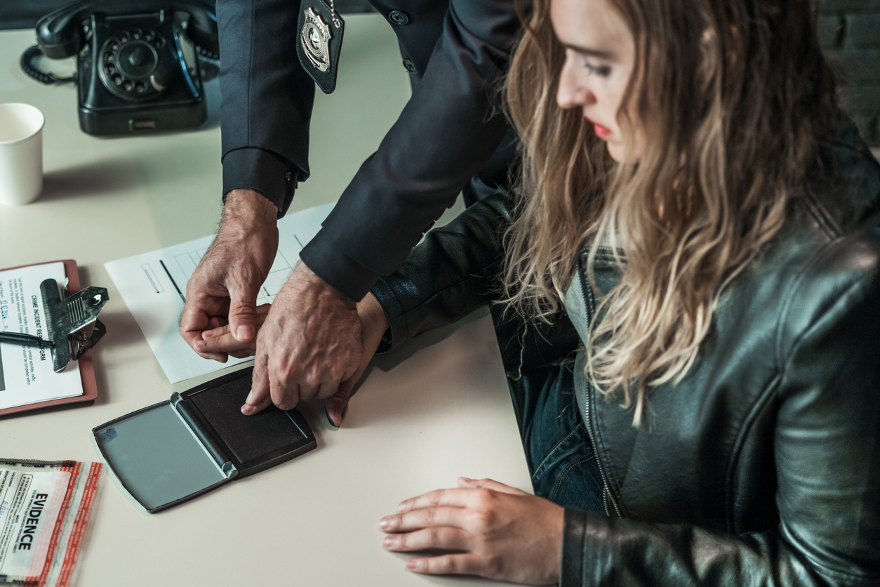 Arrested woman having her fingerprints taken