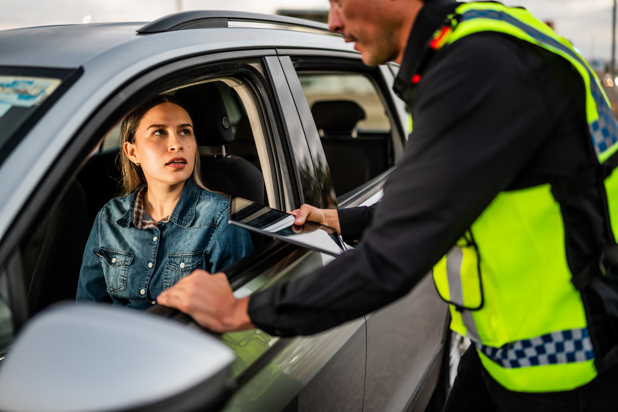 Police officer pulled over young woman and talking to her through her car window 