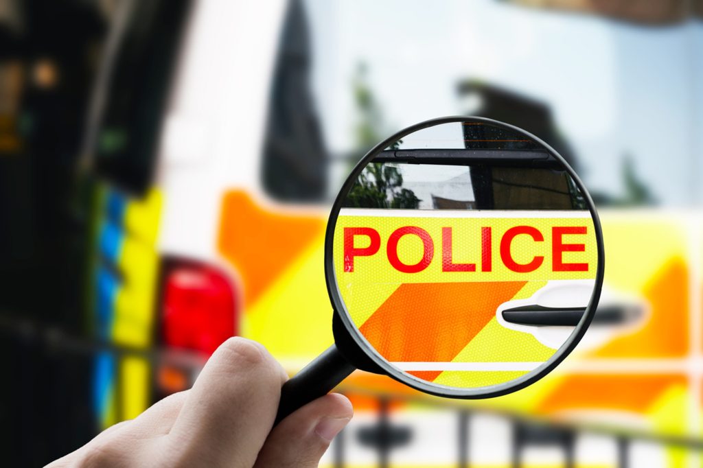 A picture of a magnifying glass highlighting the word police on the back of a police van