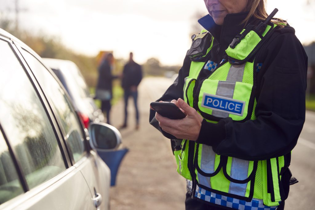Female Traffic Police Officer Wearing a bodycam Recording Details Of Road Traffic Accident On Mobile Phone