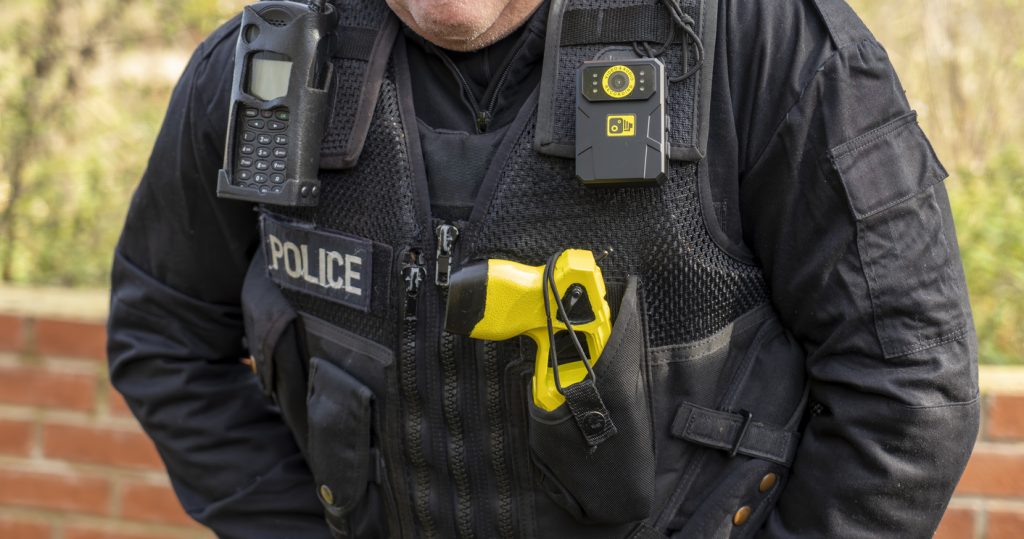 UK police officer with his body camera, taser and police radio attached to his vest.