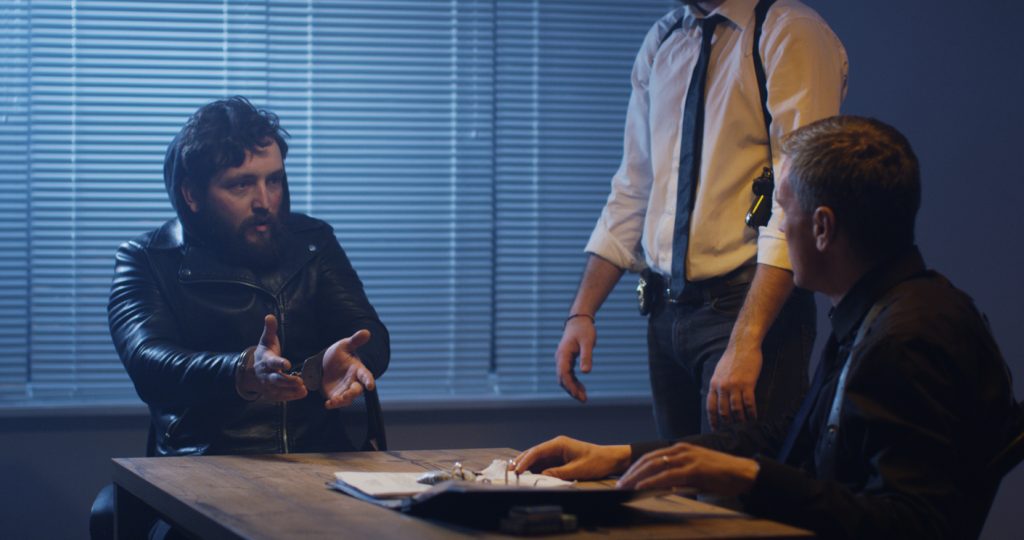 Two police officers interrogating a man in custody