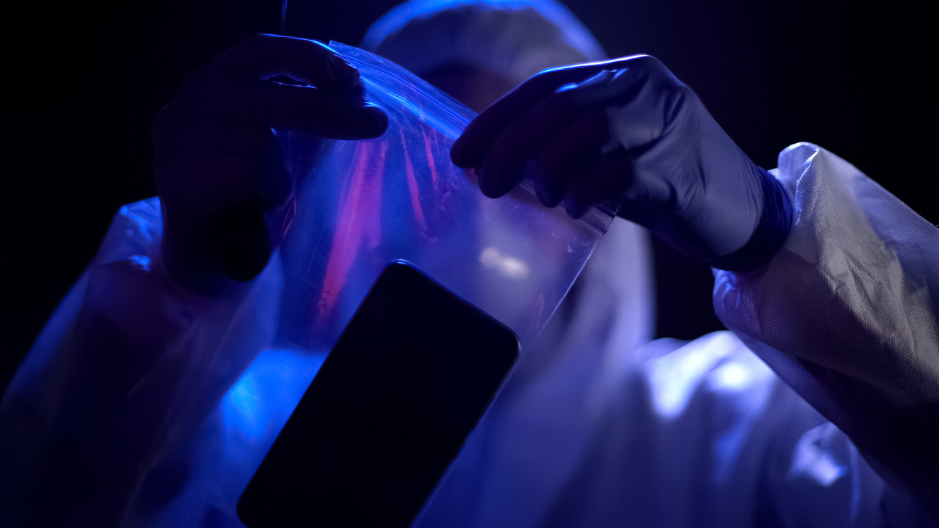 Criminal expert putting smartphone with criminal fingerprints in plastic bag