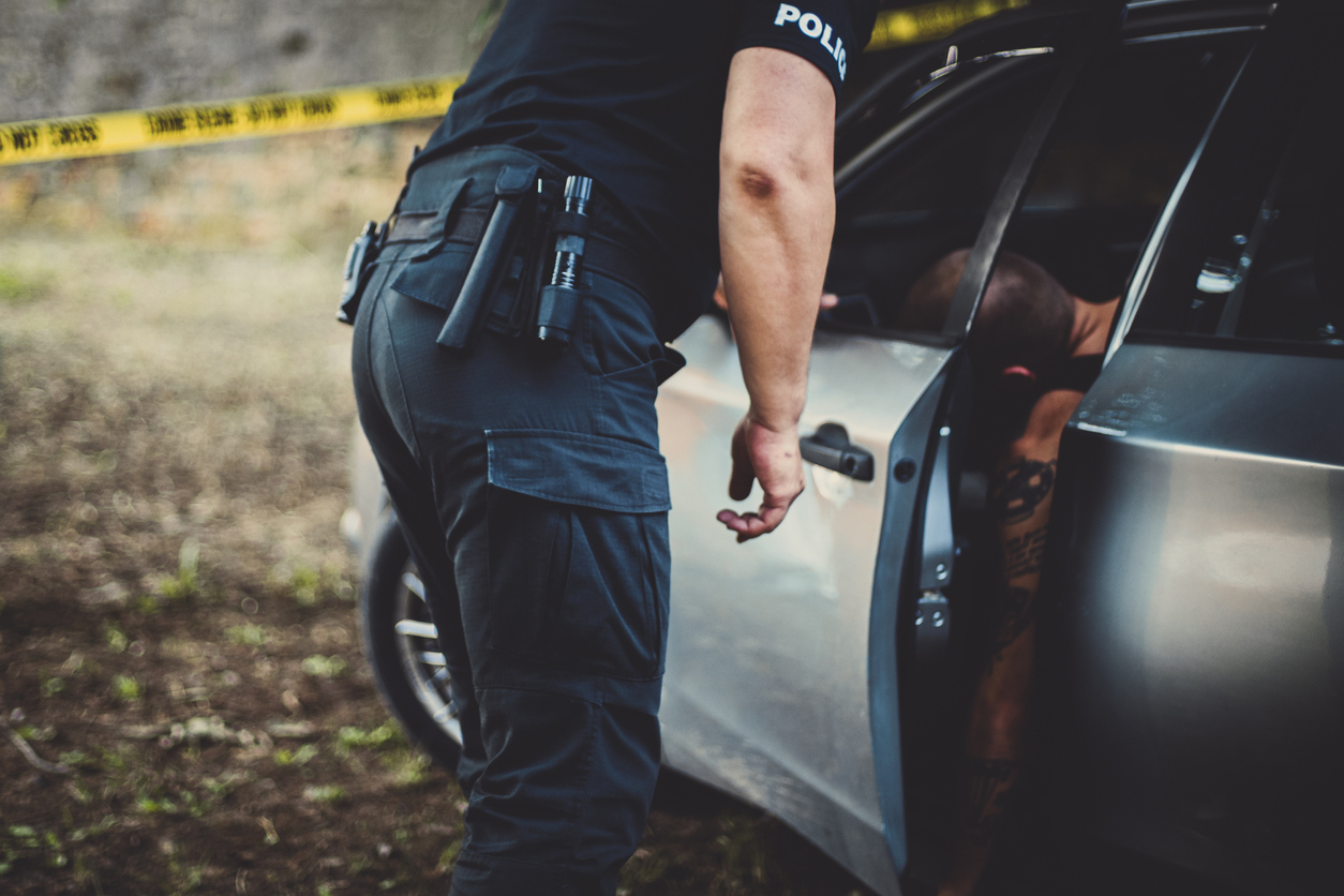 Police officer searching a car at a crime scene 