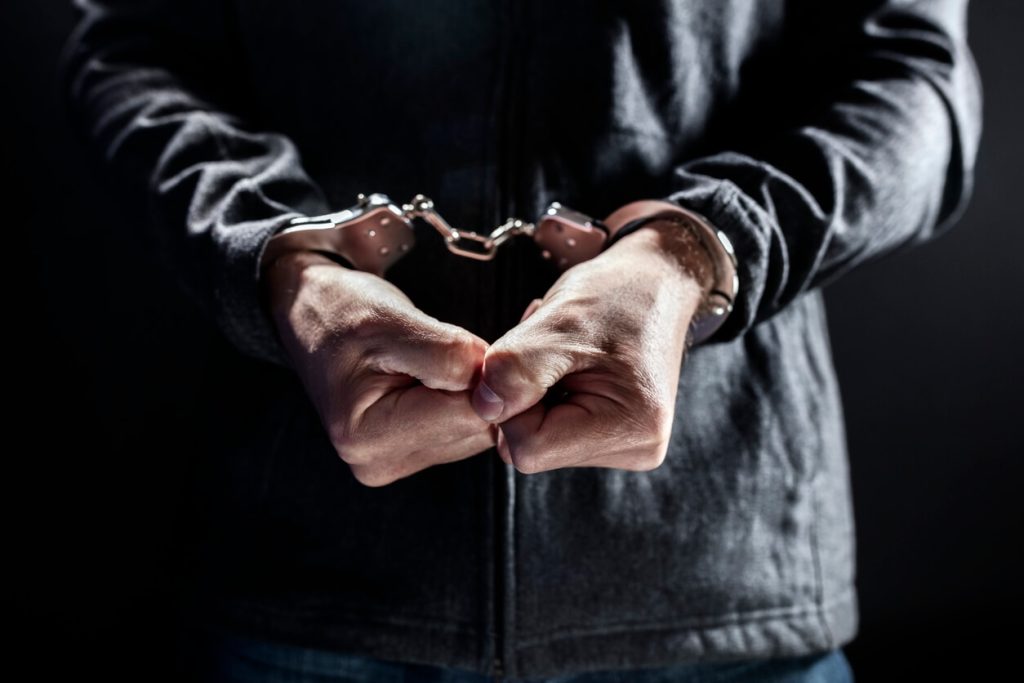 A mans hands handcuffed in front of him
