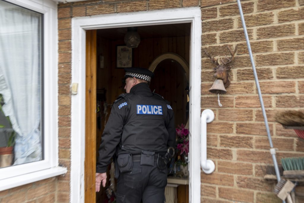 A policeman entering an elderly person's home.