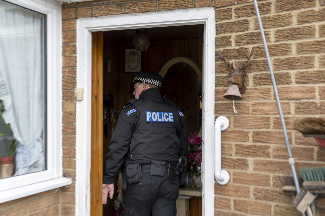 A policeman entering an elderly person's home.
